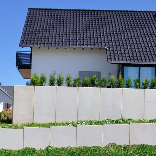 Terrassenartig angelegte Steilhangabstützung mit Stahlbeton-Stützwinkeln zwischen Wohnhäusern 
